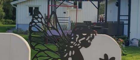 A garden with a decorative metal cutout of a fairy holding a flower.