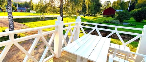 A wooden deck with white railings, a table, and chairs.