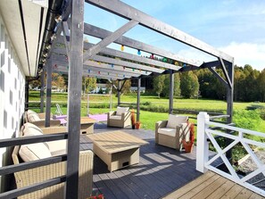 A covered outdoor seating area with wicker furniture and a pergola. - 5 Star Holiday Home in Likenas (Likenäs)