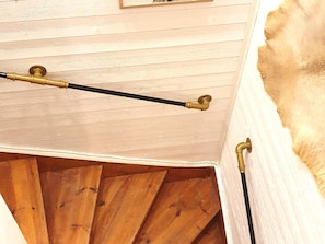 A wooden staircase with brass handrails and a white ceiling. - 5 Star Holiday Home in Likenas (Likenäs)