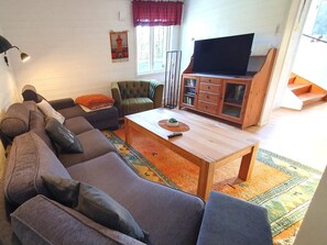 A living room with a sofa, a television, a cabinet, and a window with curtains. - 5 Star Holiday Home in Likenas (Likenäs)
