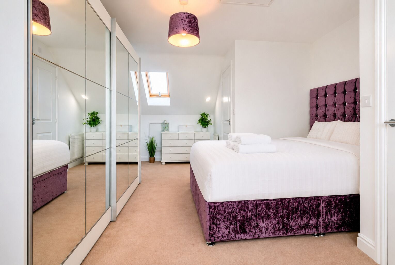 Une chambre moderne avec un grand lit, une armoire, un miroir et une petite fenêtre.