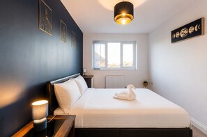 A bedroom with a bed, bedside lamp, window, and wall art. - Spacious 4-Bedroom Home in Moston with Free Parking, Garden & Fast WiFi (Manchester)