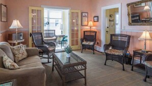Une pièce comprenant un canapé, des fauteuils en osier, une table basse et un miroir au mur.