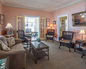 A room with a sofa, wicker chairs, a coffee table, and a mirror on the wall. - Beachfront 7-bedroom house in Wells perfect for family getaways (Wells)