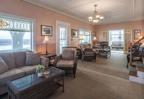 Ein geräumiges Wohnzimmer mit einer Couch, Sesseln, einem Couchtisch und einer Treppe, die zu einer weiteren Ebene führt.