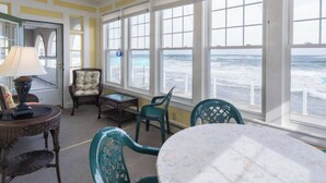 Habitación con vista al océano, que incluye una mesa, sillas y una lámpara.