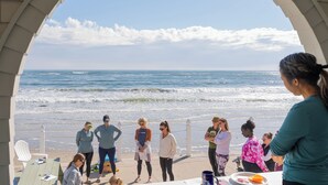 Un grupo de personas bajo un arco mirando una playa con olas.
