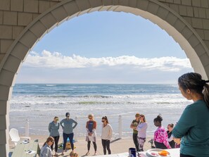 Eine Gruppe von Menschen steht unter einem Bogen und blickt auf einen Strand mit Wellen.