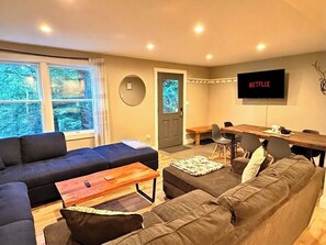 Ein Wohnzimmer mit einer Couch, einem Couchtisch, einem Fernseher und einem Essbereich.