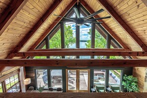 A high-ceilinged room with a wooden ceiling, large windows, and a view of a deck and outdoor seating. - Lakefront/Hot Tub/Sauna/Fire Pit (Ten Mile)