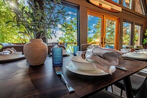 A dining table set with plates, a vase with greenery, and a fork. - Lakefront/Hot Tub/Sauna/Fire Pit (Ten Mile)