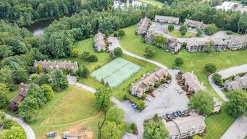 An aerial view of a residential area with houses, a tennis court, and a parking lot.