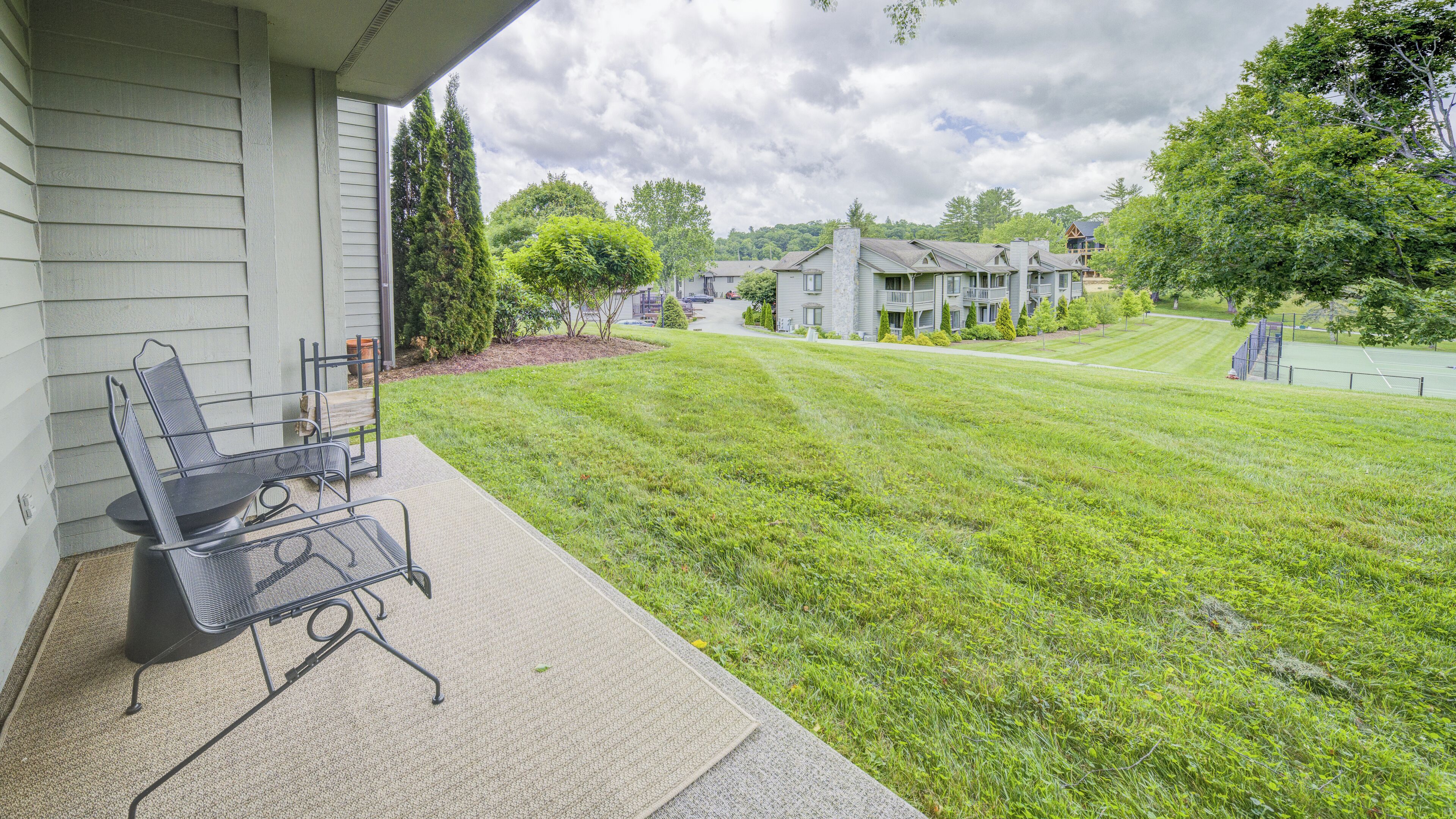 A residential property with a well-maintained lawn, a patio with outdoor furniture, and a view of neighboring houses.