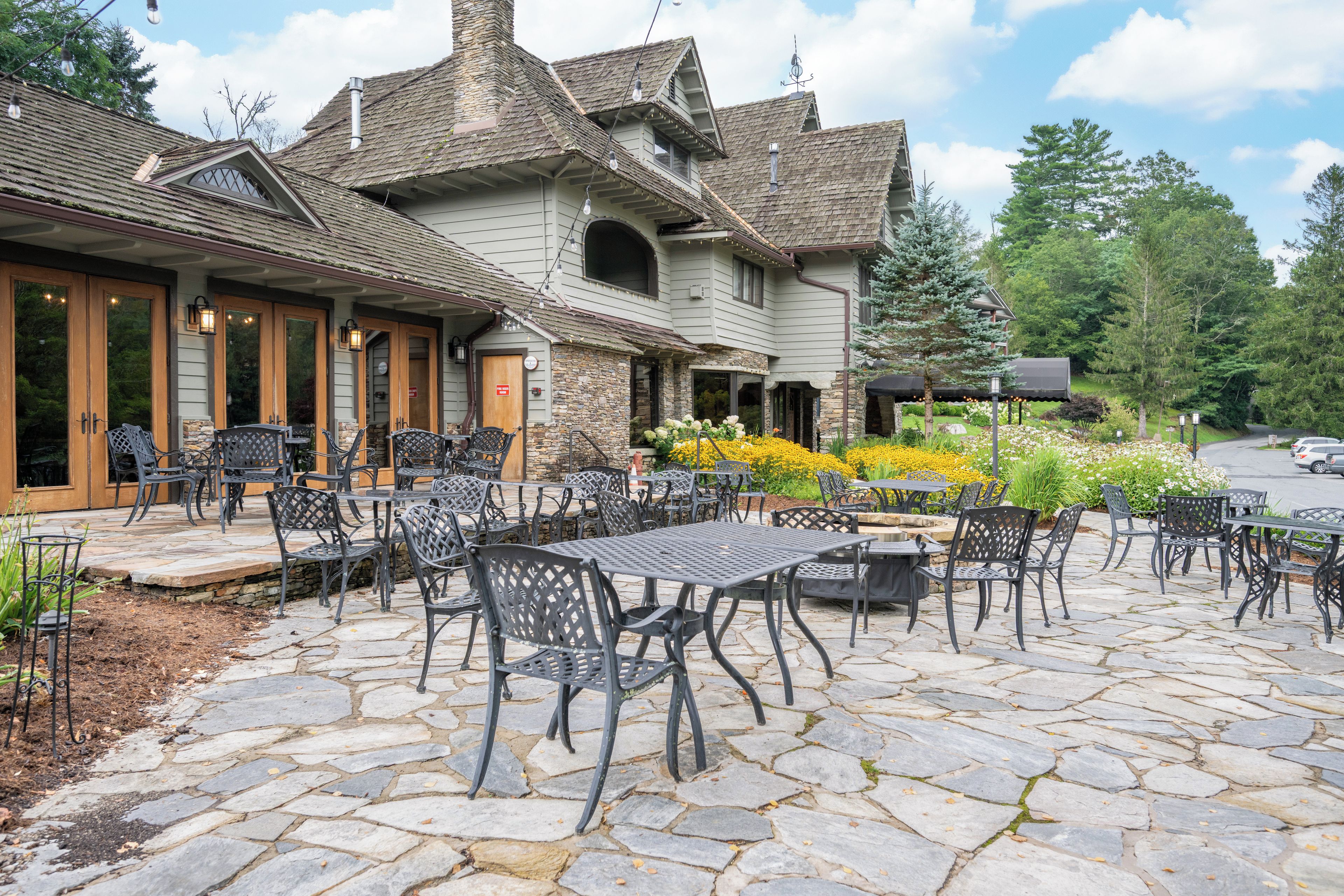 A stone-paved patio with outdoor seating and a building with a stone facade and multiple windows.