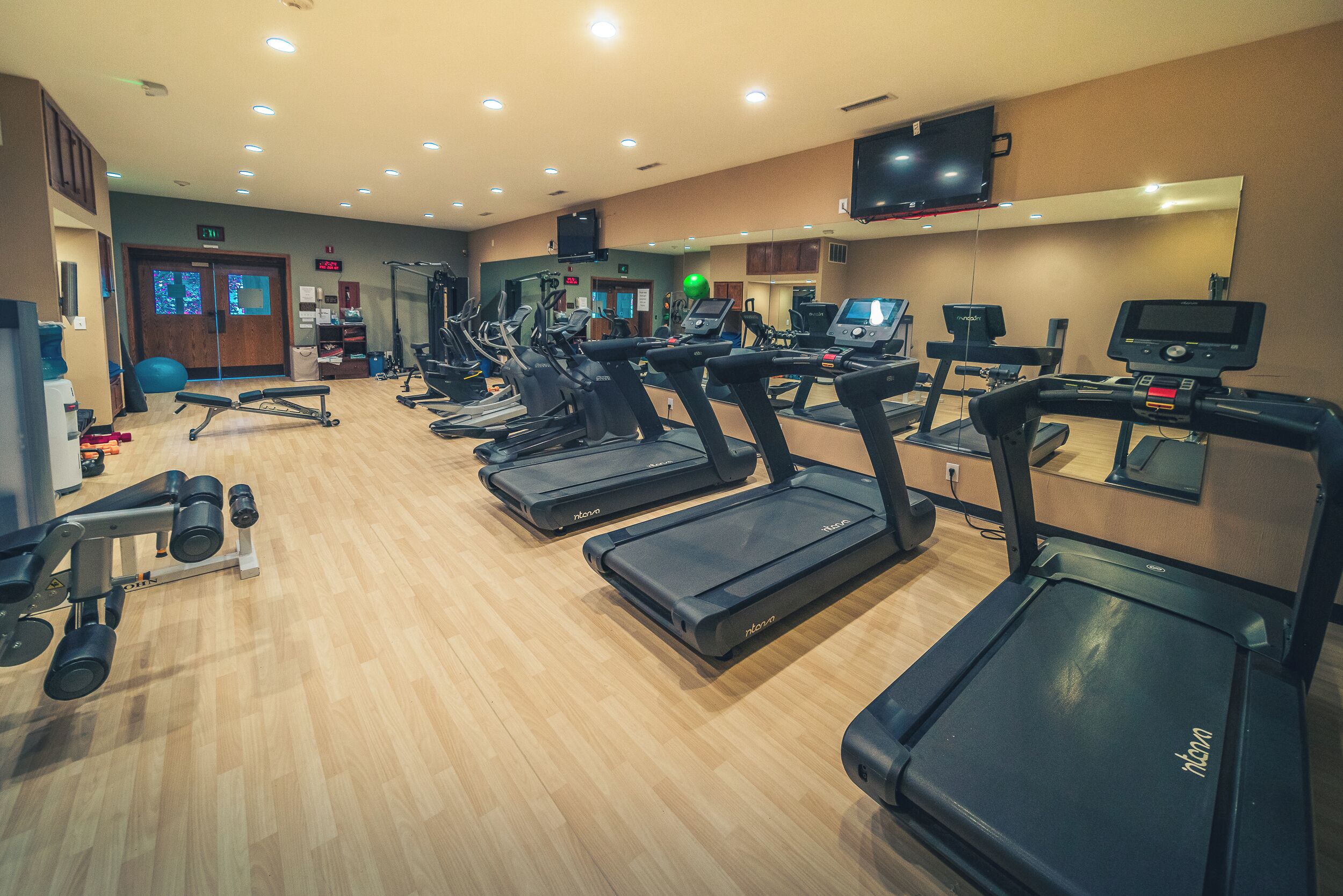 Een fitnessruimte met loopbanden, krachtapparaten en fitnessballen.