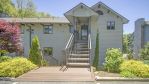 A two-story building with a front porch, a staircase, and a small garden area with shrubs and a tree. - Camelia 4 | Fireplace, Restaurant, Pool, Spa (Blowing Rock)