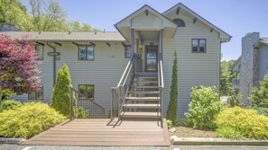 A two-story building with a front porch, a staircase, and a small garden area with shrubs and a tree. - Camelia 4 | Fireplace, Restaurant, Pool, Spa (Blowing Rock)