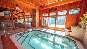 An indoor swimming pool with a wooden interior, a stone wall, and multiple windows. - Camelia 4 | Fireplace, Restaurant, Pool, Spa (Blowing Rock)