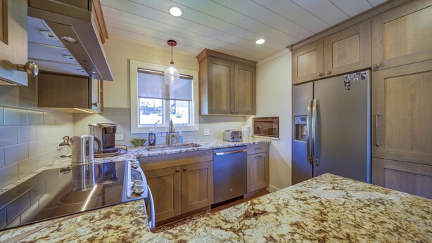 A kitchen with wooden cabinets, a stainless steel refrigerator, a coffee maker, and a microwave. - Camelia 4 | Fireplace, Restaurant, Pool, Spa (Blowing Rock)