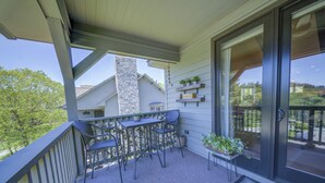 A balcony with a table and chairs, a potted plant, and a view of neighboring houses. - Camelia 4 | Fireplace, Restaurant, Pool, Spa (Blowing Rock)