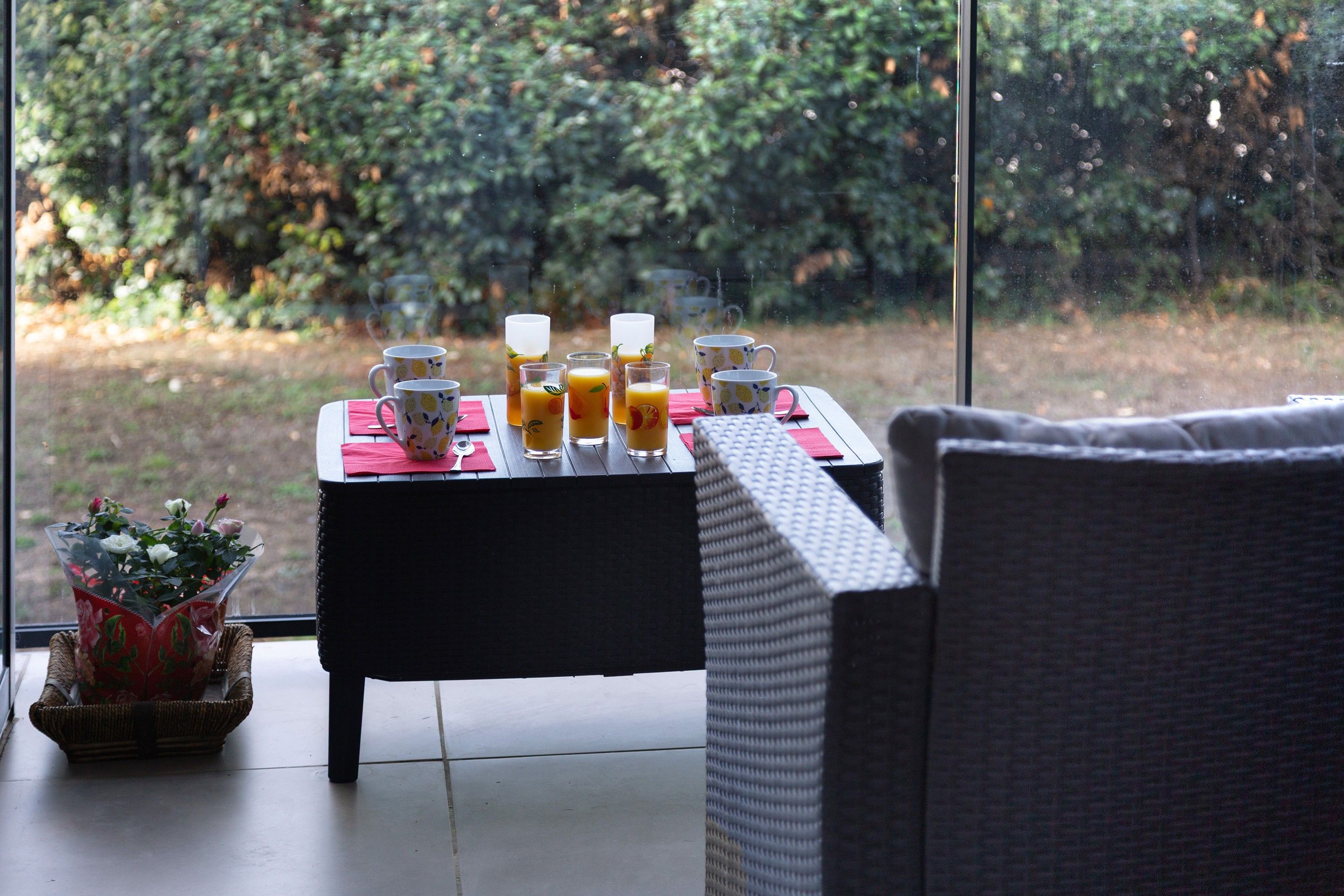 A dining table with a red napkin, a white plate, and a glass of orange juice.
