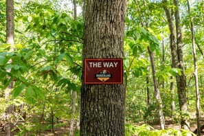 A sign on a tree in a forested area with the text 'THE WAY WANDERLAND.'