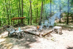 A forest campsite with a fire, chairs, and a table. - Mountain Glamping Tent with Sunrise Views & Firepit in Rising Fawn, Georgia (Rising Fawn)