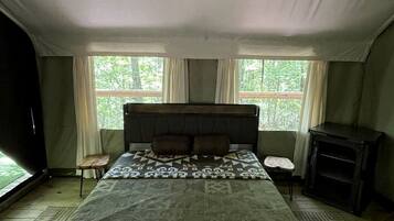 A bedroom with a large bed, a ceiling fan, a small table, and a fireplace.