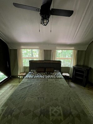 A bedroom with a large bed, a ceiling fan, a small table, and a fireplace.