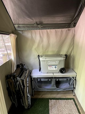 Ein gemütliches Zeltinnere mit einem Coleman-Kühler, einem kleinen Tisch und Campingausrüstung.