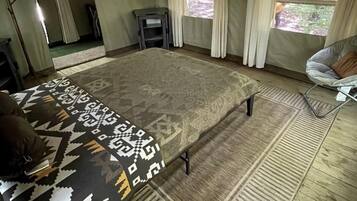 A room with a large bed, a ceiling fan, a window with curtains, and a small table.