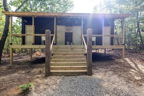 Eine Holzhütte mit einer Treppe, die zu einer Tür führt, umgeben von Bäumen.