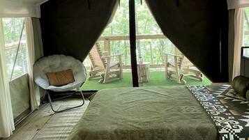 A tented room with a bed, a chair, and a ceiling fan.