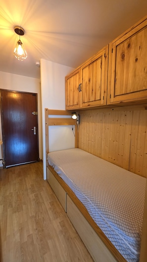 Ein Zimmer mit Etagenbett, Holzschränken, einer Tür und einer Lampe.