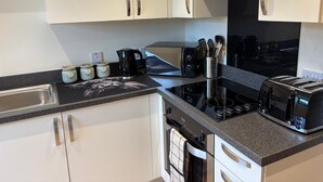 Una cucina moderna con pensili bianchi, un piano di lavoro nero, una moka, un tostapane e un bollitore.