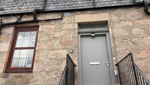 Un edificio con pareti in pietra, una porta grigia e una finestra con cornice marrone.