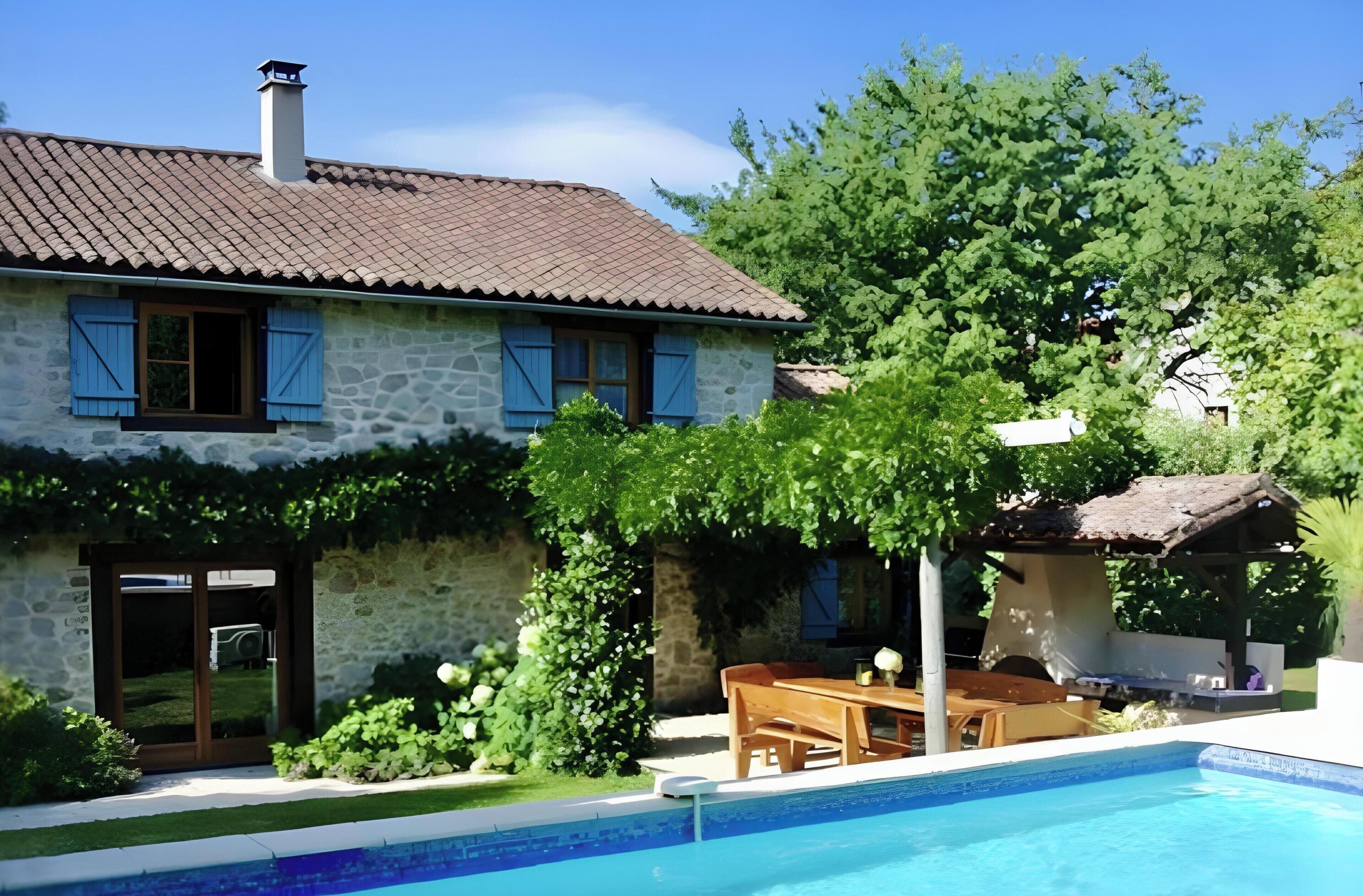 Une maison en pierre avec une piscine, une terrasse en bois et un jardin.