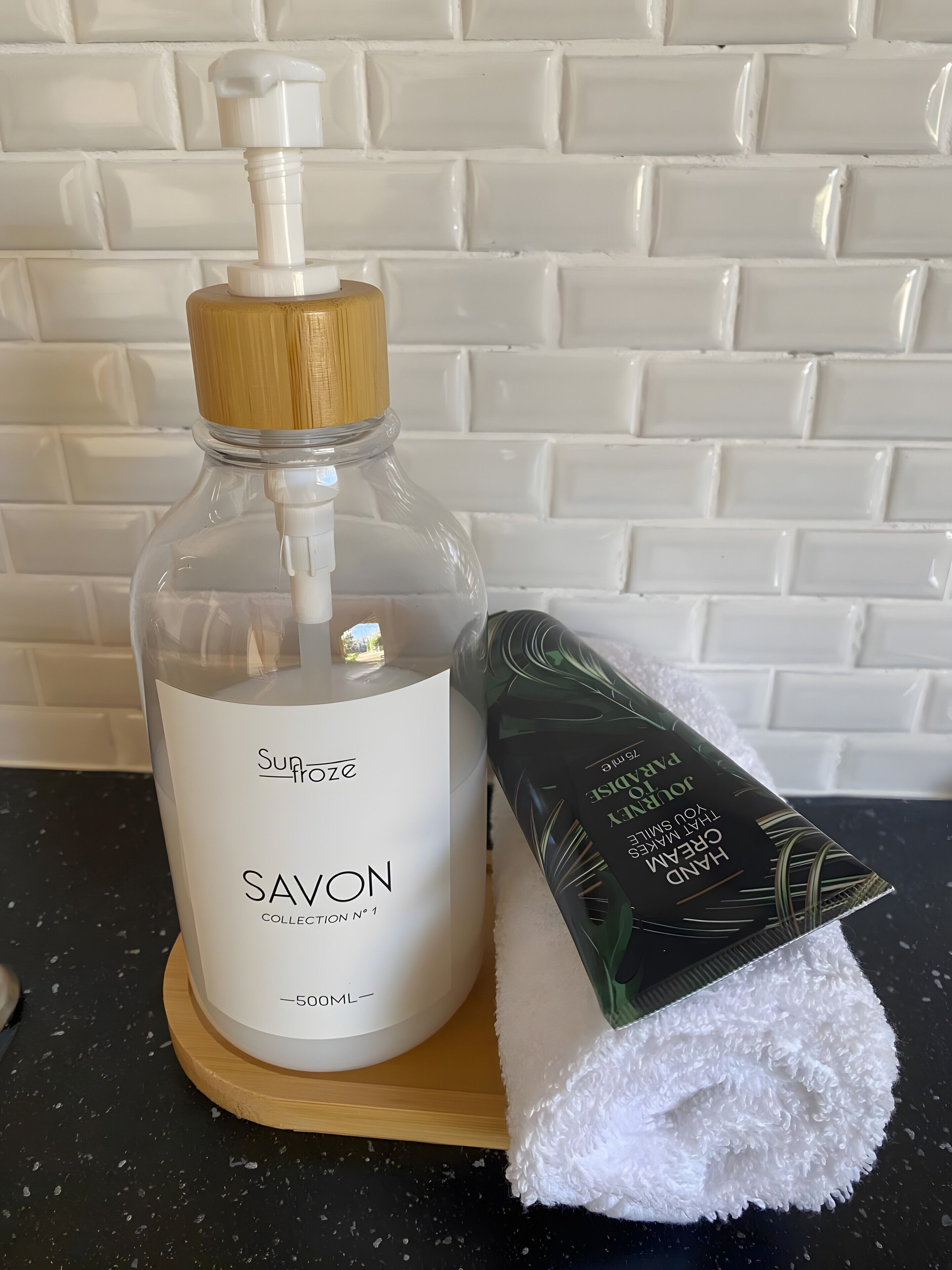 Een fles Savon zeep, een zeepstuk en een witte handdoek op een houten dienblad.