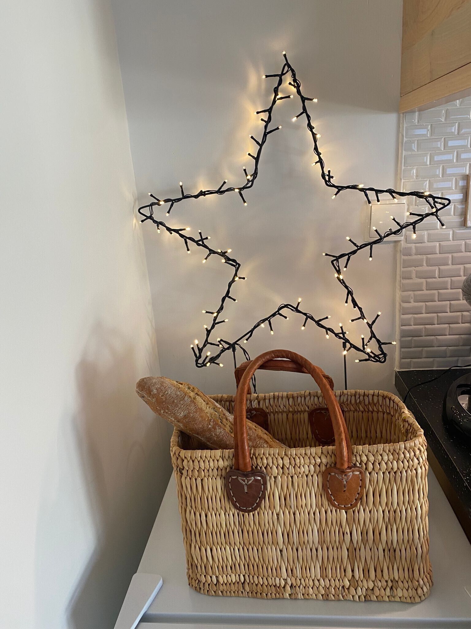 A woven basket with a baguette and a star-shaped light decoration.