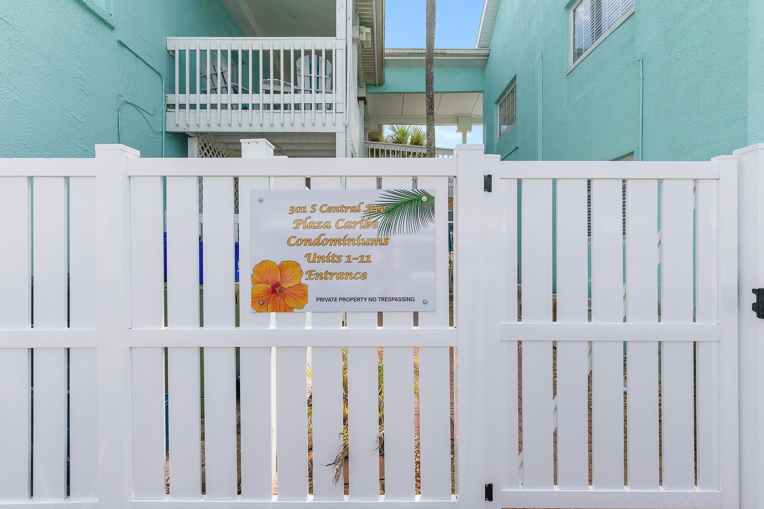A gated entrance to a condominium complex with a sign indicating the address and unit range.