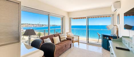 A modern living room with a large sliding glass door leading to a balcony with a sea view.