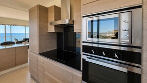 A modern kitchen with a built-in oven and microwave, a stainless steel range hood, and a view of the sea. - Apt 4 guests in Fréjus plage - sea view (Fréjus)