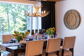 A dining area with a chandelier, a clock, and a table set for four with chairs. - Whistler Retreat with Pool/Hot Tub Free Parking (Whistler)