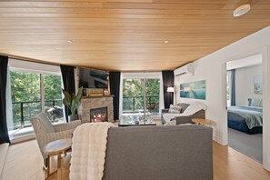 Ein modernes Wohnzimmer mit Kamin, Sitzecke und großen Fenstern mit Blick ins Freie.