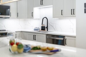 A modern kitchen with grey cabinets, a white countertop, a black faucet, and a microwave. - Whistler Retreat with Pool/Hot Tub Free Parking (Whistler)