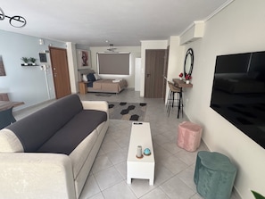 Ein Wohnzimmer mit einer Couch, einem Couchtisch, einem Fernseher und einem Essbereich mit Stühlen und einem Tisch.