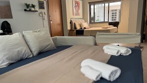 Habitación de hotel con una cama grande, un sofá, un escritorio y una ventana con vista a la calle.