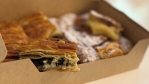 Una caja de comida con tapa verde, una taza y un fondo desenfocado.