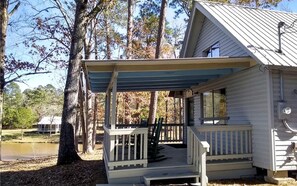 A cabin with a covered porch, a small deck, and a view of a lake.